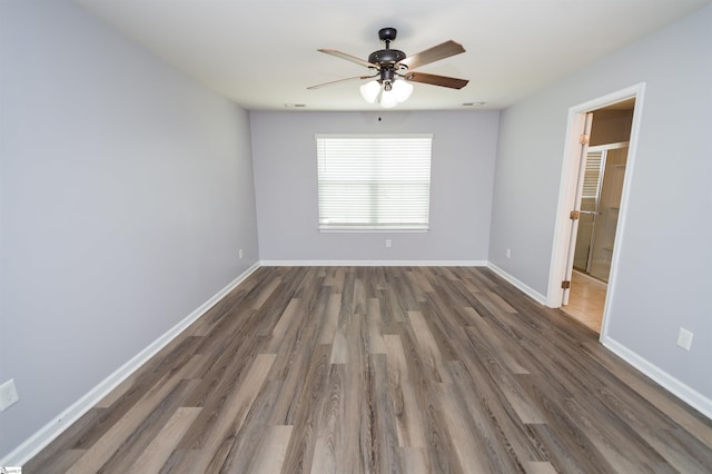 empty room with a ceiling fan, wood finished floors, and baseboards