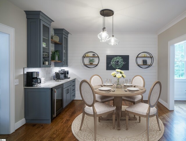 dining space featuring ornamental molding, wood walls, wine cooler, and dark hardwood / wood-style flooring