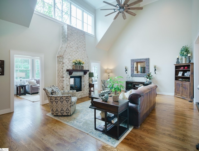 living room featuring a high ceiling, plenty of natural light, a fireplace, and ceiling fan