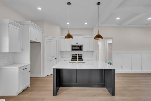 kitchen featuring tasteful backsplash, an island with sink, stainless steel appliances, white cabinetry, and light wood-type flooring