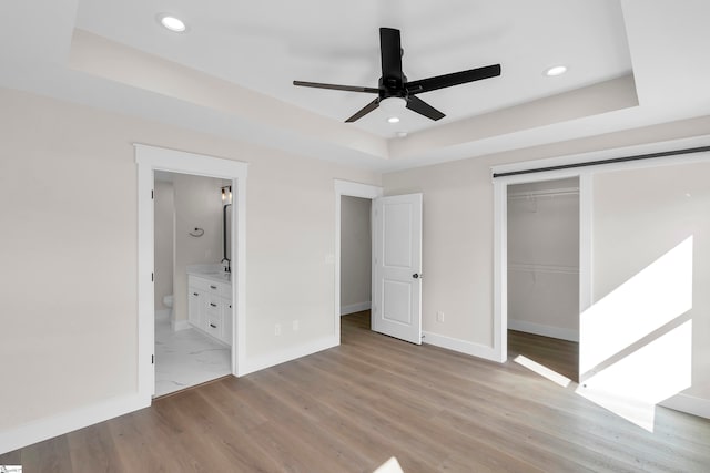 unfurnished bedroom with a closet, ceiling fan, hardwood / wood-style floors, and ensuite bath