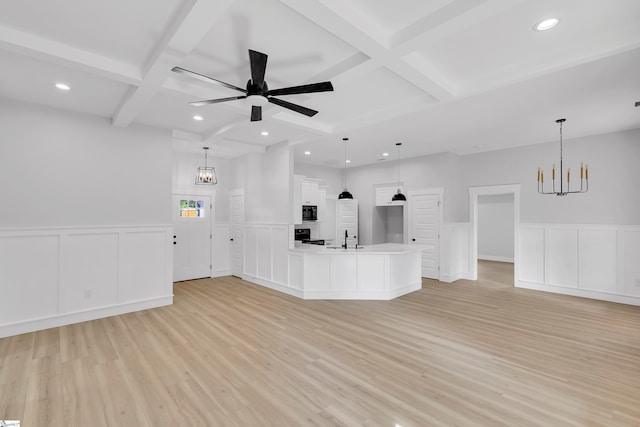 unfurnished living room with coffered ceiling, ceiling fan with notable chandelier, beam ceiling, and light hardwood / wood-style flooring