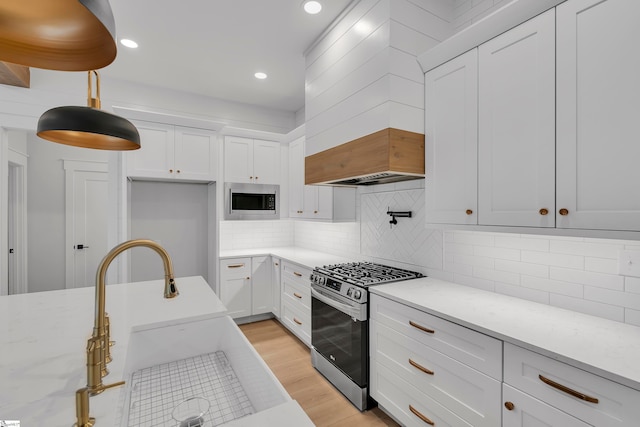 kitchen featuring white cabinetry, light hardwood / wood-style flooring, stainless steel appliances, sink, and light stone countertops