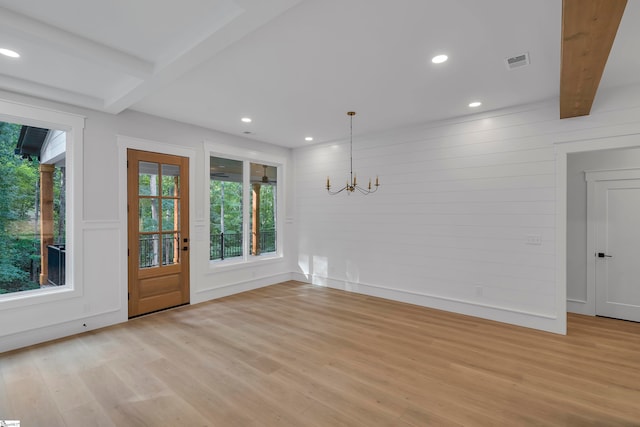 unfurnished room featuring hardwood / wood-style flooring, an inviting chandelier, and beam ceiling