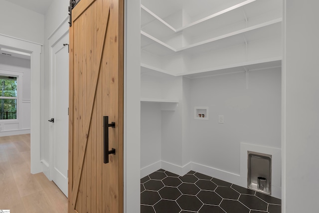 washroom with hookup for a washing machine, a barn door, and hardwood / wood-style flooring