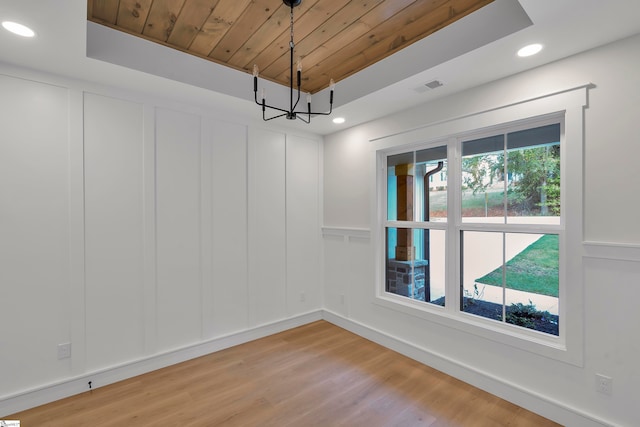 unfurnished room featuring wood ceiling, a notable chandelier, light wood-type flooring, and a tray ceiling