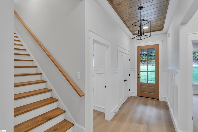 entryway with wood ceiling, an inviting chandelier, and light hardwood / wood-style flooring