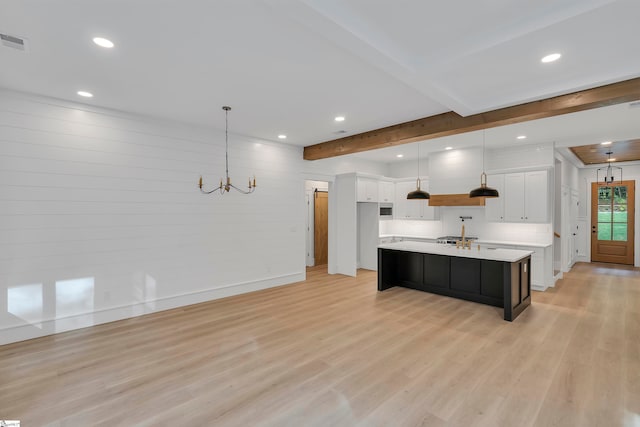 kitchen featuring a center island with sink, hanging light fixtures, white cabinets, and light hardwood / wood-style floors