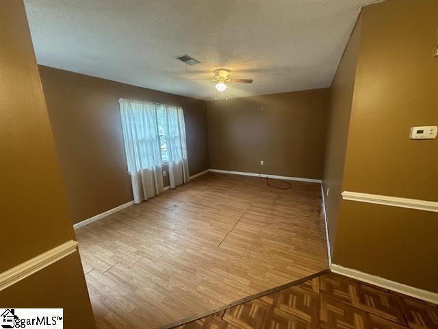 empty room featuring a textured ceiling, hardwood / wood-style flooring, and ceiling fan