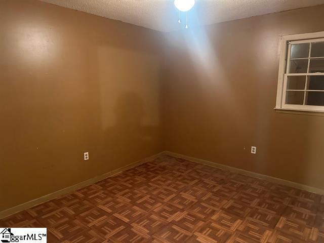 empty room with a textured ceiling, ceiling fan, and parquet floors