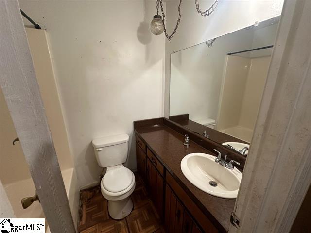 full bathroom with parquet floors, vanity, toilet, and shower / tub combination