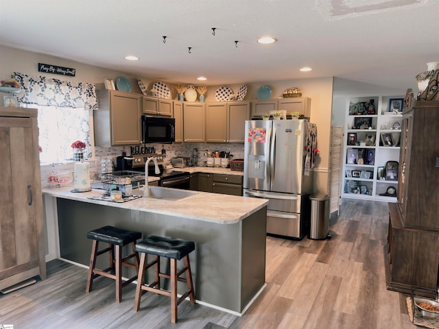 kitchen featuring kitchen peninsula, a kitchen bar, stainless steel appliances, sink, and light hardwood / wood-style floors