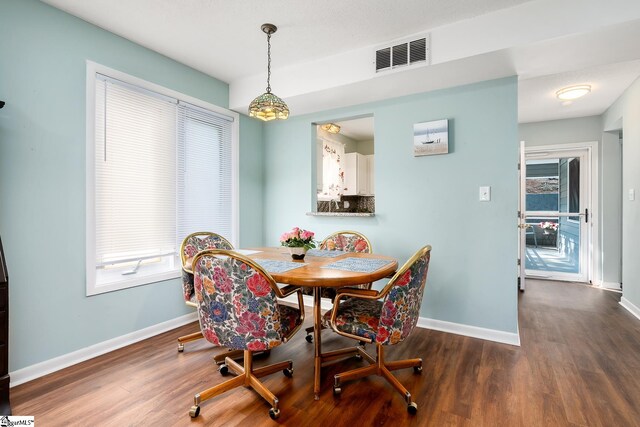 dining area with a healthy amount of sunlight, dark wood-style flooring, visible vents, and baseboards