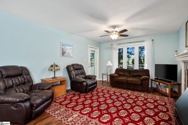 living area featuring a textured ceiling, wood finished floors, and a ceiling fan