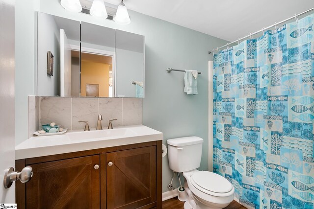 bathroom featuring vanity, a shower with shower curtain, backsplash, and toilet