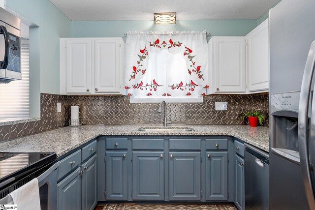 kitchen featuring tasteful backsplash, stainless steel appliances, white cabinets, and a sink