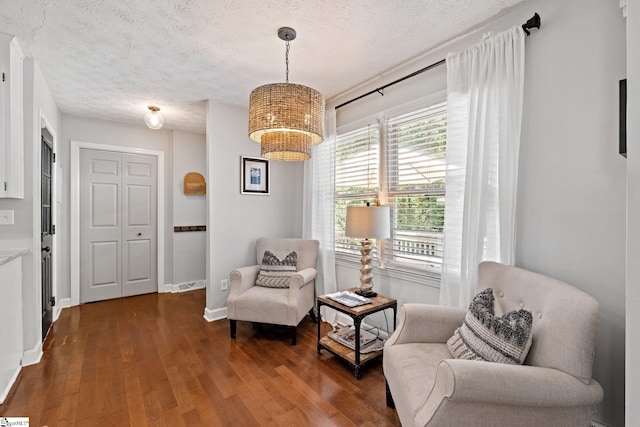 sitting room with a textured ceiling, a notable chandelier, and dark hardwood / wood-style flooring