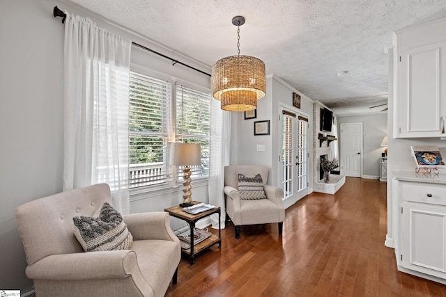 sitting room with dark wood-type flooring, a textured ceiling, french doors, and a notable chandelier