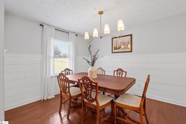 dining space with dark hardwood / wood-style floors, an inviting chandelier, and a textured ceiling