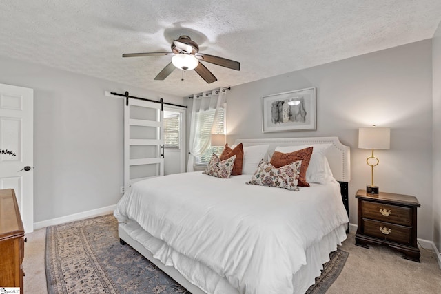 bedroom with light carpet, a textured ceiling, ceiling fan, and a barn door