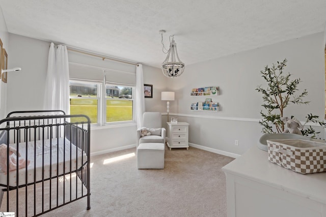 bedroom with carpet flooring, an inviting chandelier, a textured ceiling, and a crib