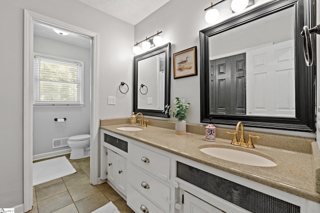 bathroom featuring a textured ceiling, vanity, toilet, and tile patterned floors