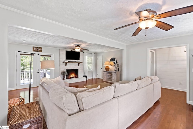 living room featuring wood-type flooring, a wealth of natural light, a fireplace, and ceiling fan