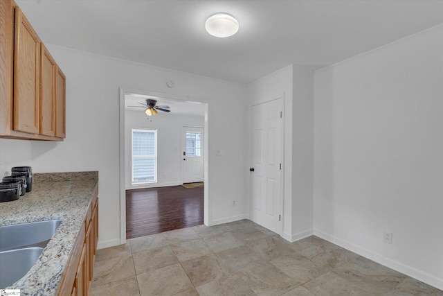 kitchen featuring ceiling fan, light stone countertops, light hardwood / wood-style floors, and sink