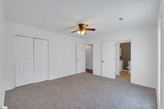 unfurnished bedroom with light colored carpet, ensuite bathroom, ceiling fan, and a closet