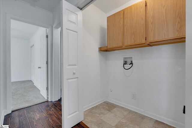 laundry area featuring hookup for a washing machine, light hardwood / wood-style flooring, and cabinets