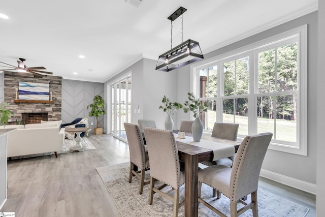 dining space with light hardwood / wood-style floors, ceiling fan, and a stone fireplace