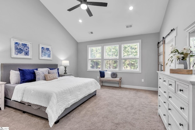 bedroom with a barn door, ceiling fan, light carpet, and high vaulted ceiling