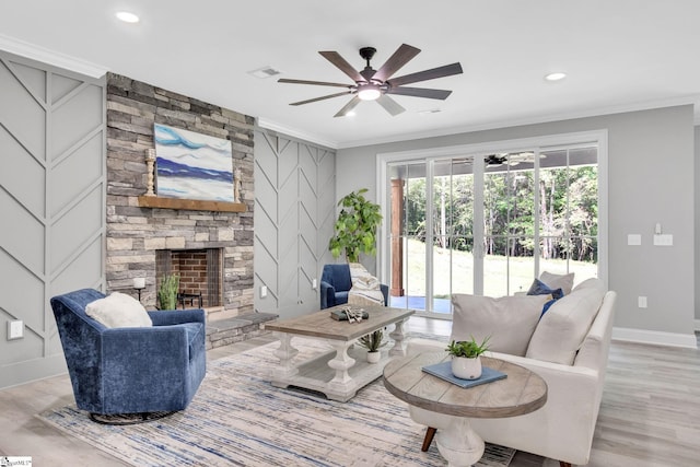 living room featuring light hardwood / wood-style flooring, ceiling fan, ornamental molding, and a fireplace