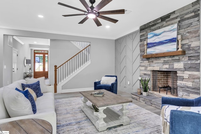 living room featuring ceiling fan, ornamental molding, light wood-type flooring, and a fireplace