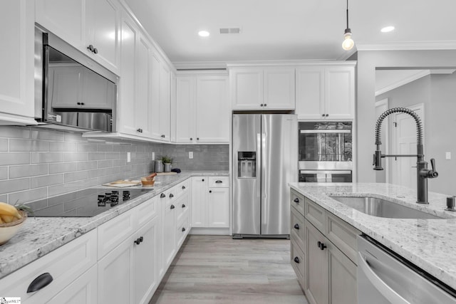 kitchen with pendant lighting, crown molding, stainless steel appliances, sink, and white cabinetry