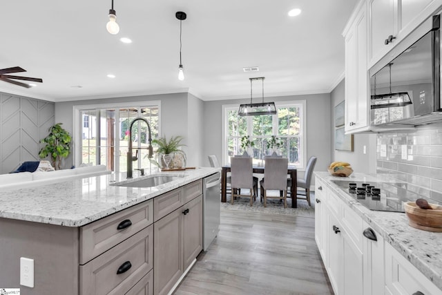 kitchen with white cabinets, stainless steel appliances, sink, ceiling fan, and a kitchen island with sink