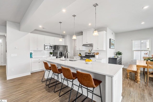 kitchen with white cabinetry, a center island with sink, stainless steel appliances, and light hardwood / wood-style floors