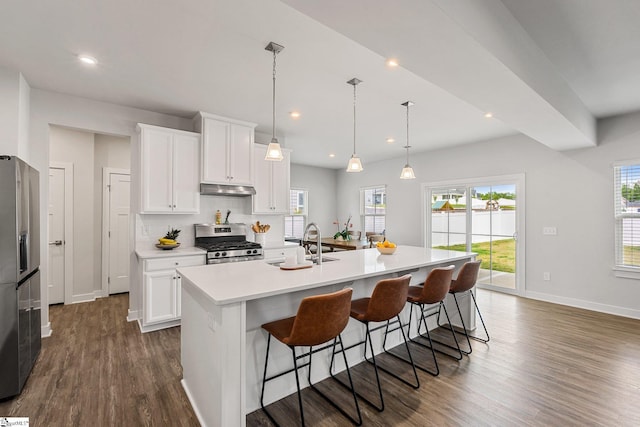 kitchen featuring decorative light fixtures, a kitchen island with sink, dark wood-type flooring, stainless steel appliances, and white cabinets