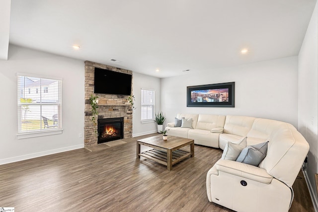 living room featuring dark hardwood / wood-style floors and a stone fireplace