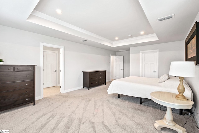 bedroom with a tray ceiling and light carpet