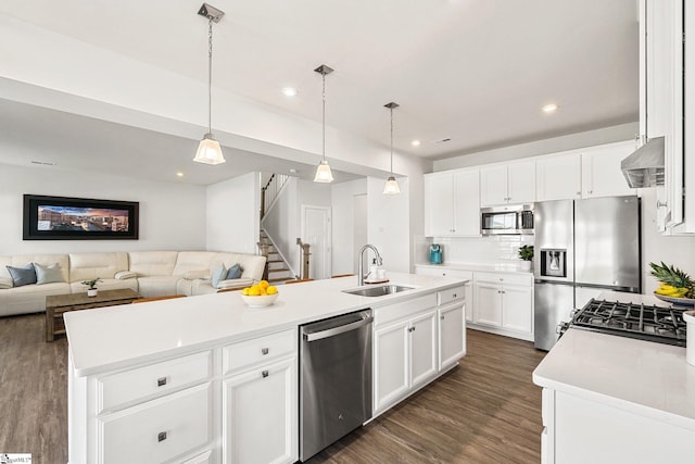 kitchen with white cabinets, appliances with stainless steel finishes, sink, dark wood-type flooring, and a kitchen island with sink