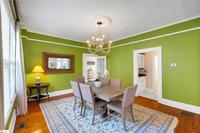 dining area with plenty of natural light, light hardwood / wood-style flooring, and a notable chandelier