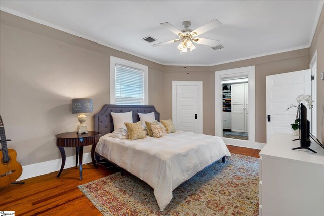 bedroom featuring crown molding, wood-type flooring, ceiling fan, and a closet