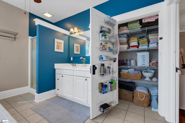 interior space featuring a shower with shower door, ceiling fan, vanity, and tile patterned floors