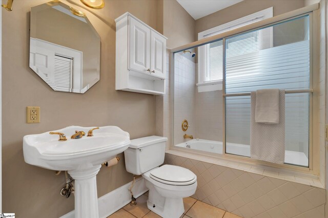 bathroom with tiled shower / bath, toilet, and tile patterned floors