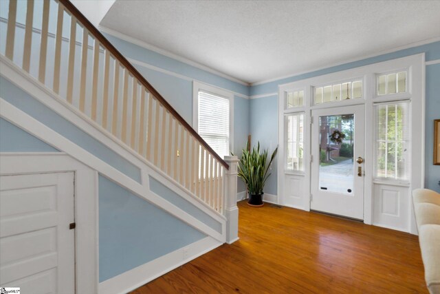 foyer with ornamental molding, a textured ceiling, and hardwood / wood-style floors