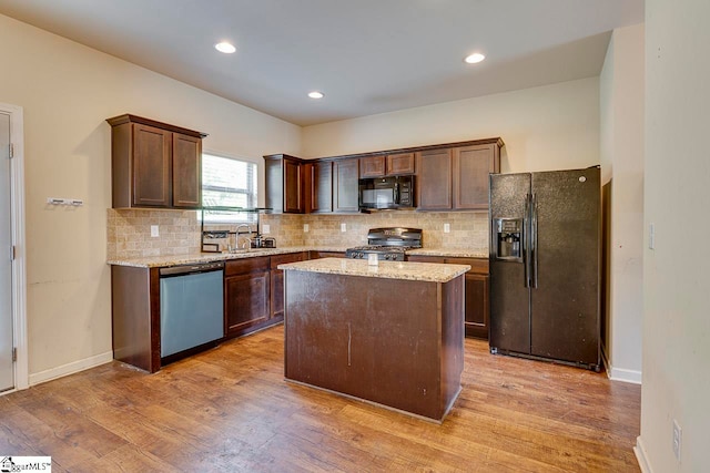 kitchen featuring dark brown cabinets, black appliances, light hardwood / wood-style flooring, a center island, and light stone counters