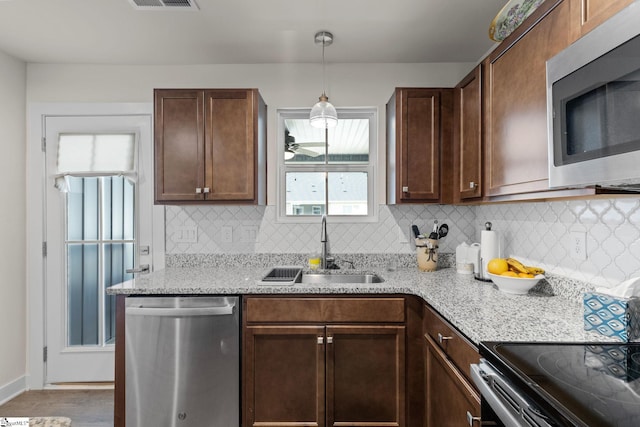 kitchen with light stone countertops, backsplash, stainless steel appliances, sink, and hardwood / wood-style flooring