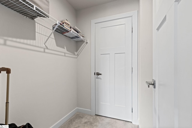 walk in closet featuring light colored carpet