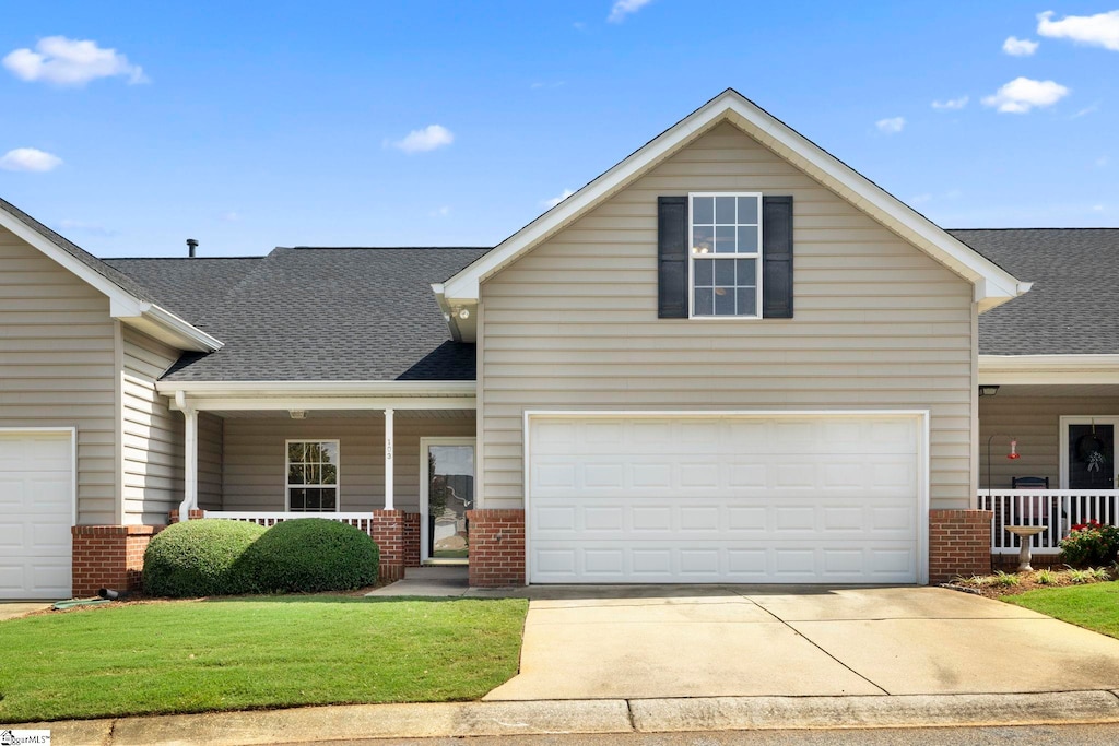 front facade featuring a garage, covered porch, and a front yard